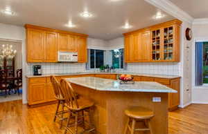 Kitchen with black electric stovetop, a kitchen island, a kitchen bar, and light hardwood / wood-style flooring