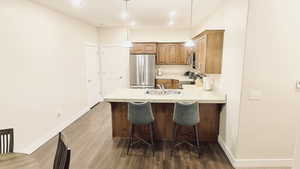 Kitchen with kitchen peninsula, appliances with stainless steel finishes, Knotty Alder Cabinets, LVP flooring and pendent lights