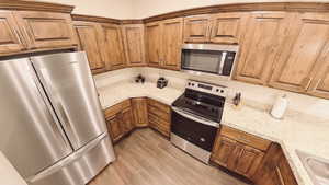 Kitchen with kitchen peninsula, appliances with stainless steel finishes, Knotty Alder Cabinets, LVP flooring and pendent lights