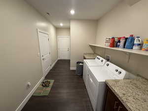 Laundry room with dark hardwood / wood-style flooring and washing machine and clothes dryer