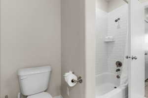 Bathroom with toilet and shower / bathtub combination with curtain