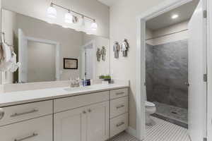 Bathroom with vanity, toilet, and tiled shower