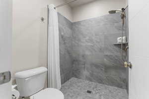 Bathroom featuring a shower with shower curtain and toilet