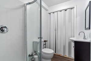 Bathroom with a shower, wood-type flooring, vanity, and toilet