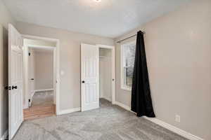 Unfurnished bedroom featuring a closet, light colored carpet, and a textured ceiling