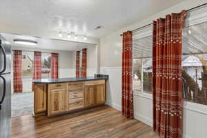 Kitchen featuring kitchen peninsula, refrigerator, dark wood-type flooring, and a textured ceiling