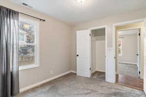 Unfurnished bedroom with carpet flooring, a textured ceiling, and a closet