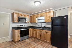 Kitchen with hardwood / wood-style floors, sink, decorative backsplash, a textured ceiling, and stainless steel appliances