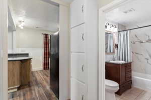 Full bathroom featuring shower / tub combo, vanity, a textured ceiling, wood-type flooring, and toilet