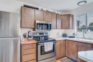 Kitchen with sink, appliances with stainless steel finishes, and tasteful backsplash