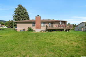 Back of house featuring a lawn, a wooden deck, and cooling unit