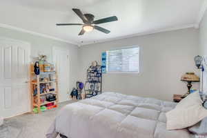 Bedroom with light carpet, ceiling fan, and ornamental molding