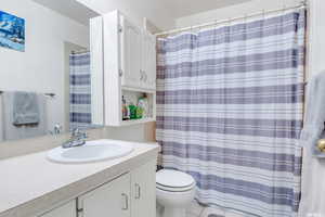 Bathroom featuring tile patterned flooring, a shower with curtain, vanity, and toilet