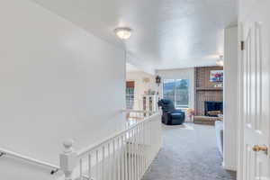 Corridor featuring a textured ceiling and light carpet