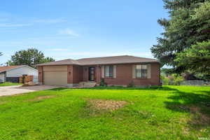 Single story home with a garage and a front lawn