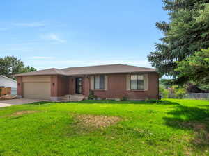 Single story home with a garage and a front lawn