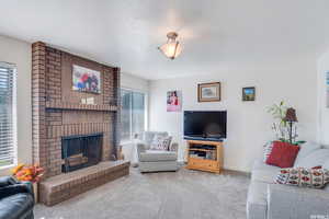 Carpeted living room with plenty of natural light and a brick fireplace