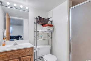 Bathroom featuring vanity, a shower with shower door, a textured ceiling, and toilet