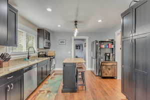 Kitchen featuring a kitchen bar, appliances with stainless steel finishes, sink, a kitchen island, and hanging light fixtures