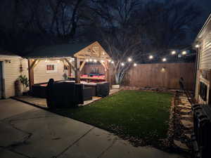 Yard at night featuring a patio, an outdoor hangout area, and garage/shop