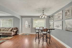 Dining area featuring hardwood / wood-style floors, a textured ceiling, and an inviting chandelier