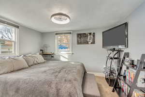 Carpeted bedroom featuring multiple windows and a textured ceiling