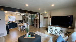 Living room with a textured ceiling, light hardwood / wood-style flooring, a notable chandelier, and sink