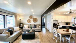 Living room with sink, a textured ceiling, light hardwood / wood-style floors, and an inviting chandelier