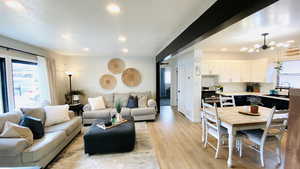 Living room featuring a textured ceiling, a notable chandelier, light hardwood / wood-style flooring, and sink