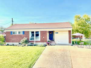 View of front of property with a garage and pretty floral landscaping