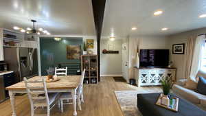 Interior space with a textured ceiling, light hardwood / wood-style flooring, and a notable chandelier