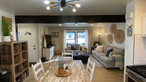 Living room with beam ceiling, light wood-type flooring, and a notable chandelier