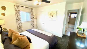 Bedroom with dark carpet, ceiling fan, and ensuite bath