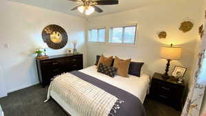 Bedroom with ceiling fan and dark colored carpet