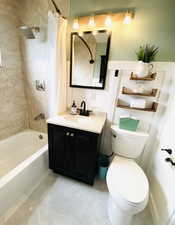 Full bathroom featuring toilet, shower / bath combo, and vanity