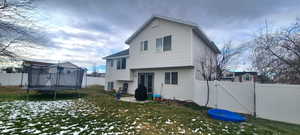 Rear view of property with a lawn and a trampoline