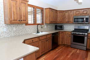 Kitchen featuring sink, tasteful backsplash, dark hardwood / wood-style flooring, vaulted ceiling, and appliances with stainless steel finishes