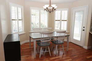 Dining area featuring a notable chandelier and dark wood-type flooring