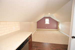 Additional living space featuring lofted ceiling and a textured ceiling