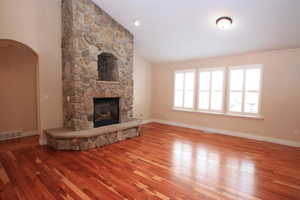 Unfurnished living room with hardwood / wood-style flooring, a fireplace, and vaulted ceiling