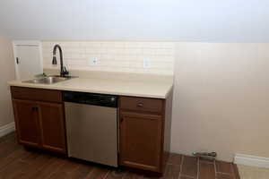 Kitchen with dishwasher, decorative backsplash, gas stubbed for stove, and sink