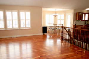 Living room with light wood-type flooring, sink, and an inviting chandelier