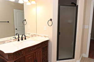 Primary bathroom with vanity, tile patterned floors, and a shower with shower door