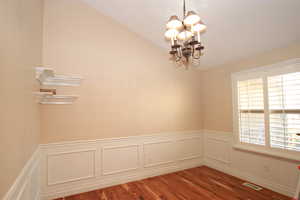 Formal front room with a chandelier, wood-type flooring, and vaulted ceiling