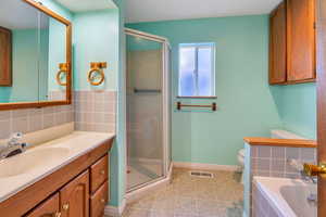 Full bathroom with backsplash, vanity, tile patterned flooring, shower with separate bathtub, and toilet