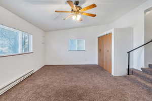 Empty room with carpet floors, baseboard heating, and ceiling fan