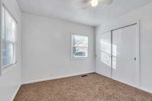 Unfurnished bedroom featuring ceiling fan, a closet, and carpet