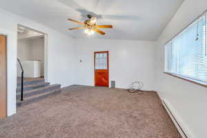 Spare room featuring carpet flooring, ceiling fan, a baseboard radiator, and vaulted ceiling