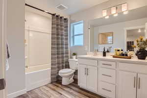 Full bathroom with vanity, LVP flooring, toilet, and shower / bath combo with shower curtain