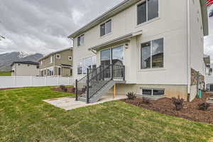 Back of property featuring a lawn, a mountain view, central AC unit, and a patio